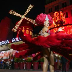 Una bailarina del Moulin Rouge baila bajo las nuevas aspas del Molino de Viento del Moulin Rouge para celebrar su regreso a la actividad en París. Catorce meses después de su caída, las alas del Moulin Rouge han sido reinstaladas y vuelven a moverse, reviviendo una tradición de más de 135 años. Con más de doce metros de diámetro, las alas, que se han convertido en una atracción turística parisina, ahora funcionan con un motor eléctrico hecho a medida para el cabaret parisino. | Foto:DIMITAR DILKOFF / AFP