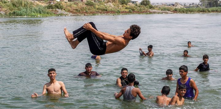 Un joven se sumerge en el río Éufrates para refrescarse durante los cortes de electricidad provocados por una ola de calor extrema en el distrito de Mishkhab, al sur de la ciudad de Nayaf, en el centro de Irak.