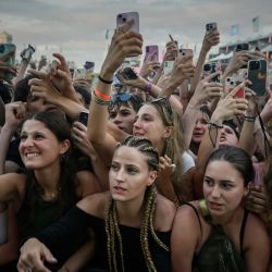 Los asistentes al festival sostienen sus teléfonos móviles mientras se estiran para ver frente al escenario durante la 41.ª edición de las Francofolies de la Rochelle 2025, en La Rochelle, suroeste de Francia. | Foto:Philippe Lopez / AFP