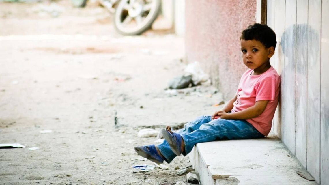 A child sits against a wall.