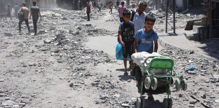 Palestinos buscan objetos para rescatar entre los escombros de los edificios destruidos un día antes en los ataques israelíes contra el barrio de Al-Daraj en la ciudad de Gaza.