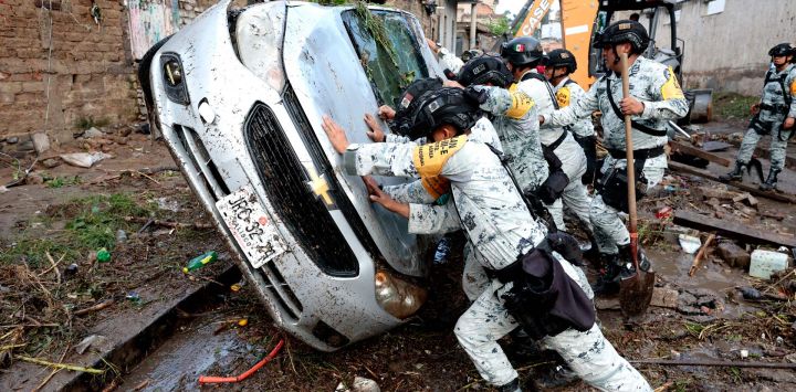Soldados del ejército revierten un vehículo dañado por las inundaciones repentinas causadas por las fuertes lluvias en Zapopan, Jalisco, México.