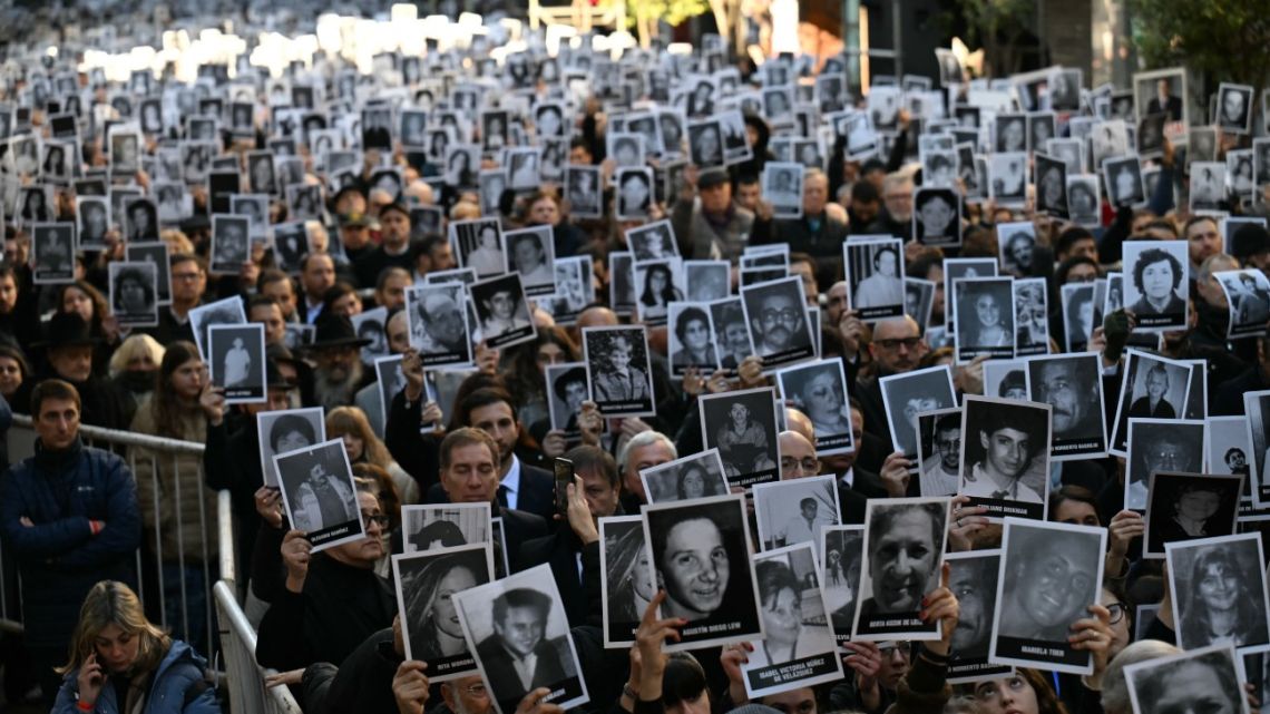 People hold pictures of victims during a ceremony to commemorate the 31st anniversary the Mutual Israelite Association of Argentina (AMIA) bombing attack which left 85 dead and more than 300 wounded, in Buenos Aires on July 18, 2025. 