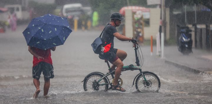 Personas pasan a través de una calle anegada, en Ciudad Quezon, Filipinas. Wipha se intensificó hasta convertirse en una severa tormenta tropical a medida que se alejaba de Filipinas, trayendo fuertes vientos y lluvias torrenciales a muchas áreas.