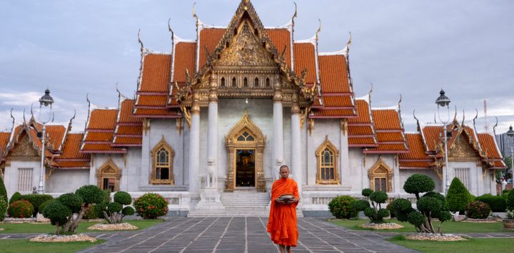 Un monje budista se prepara para recoger limosnas frente a un templo en Bangkok, Tailandia.