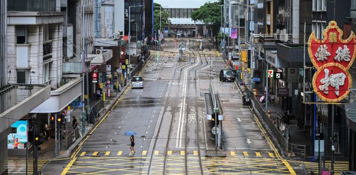 Una mujer cruza una calle vacía en el distrito Central mientras el tifón Wipha avanza hacia Hong Kong.