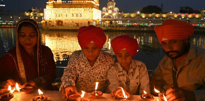 Devotos sijs encienden lámparas de barro en el Templo Dorado iluminado para conmemorar el aniversario del nacimiento del gurú sij Harkrishan Sahib en Amritsar, India.