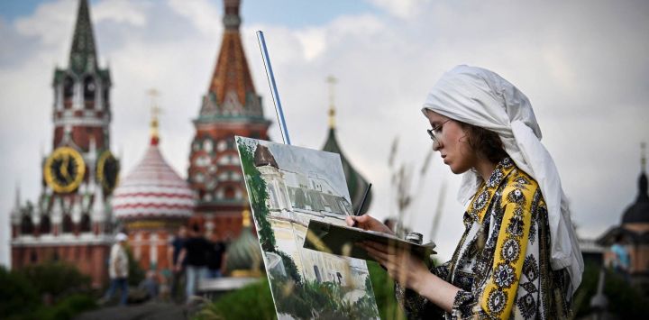 Una niña pinta frente a la Torre Spasskaya del Kremlin y la Catedral de San Basilio en el centro de Moscú, Rusia.