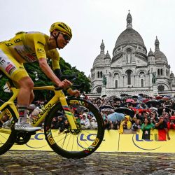 El ciclista esloveno Tadej Pogacar, del equipo UAE Team Emirates - XRG, luciendo el maillot amarillo de líder de la general, pasa en bicicleta junto a la Basílica del Sacré-Coeur en la Butte de Montmartre durante la 21.ª y última etapa de la 112.ª edición del Tour de Francia, de 132,3 km entre Mantes-la-Ville y la avenida de los Campos Elíseos de París. | Foto:LOIC VENANCE / AFP