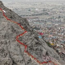 En esta vista aérea, familiares de las víctimas de las protestas antigubernamentales de 2022-2023, vestidos de rojo, participan en una ceremonia conmemorativa en el Cerro San Cristóbal de Lima, Perú. | Foto:CONNIE FRANCE / AFP