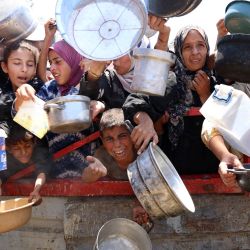 Palestinos se congregan en un punto de distribución de sopa de lentejas en la ciudad de Gaza, al norte de la Franja de Gaza. | Foto:OMAR AL-QATTAA / AFP