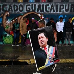 Un partidario del presidente venezolano, Nicolás Maduro, sostiene una imagen del fallecido presidente venezolano, Hugo Chávez, durante una manifestación para celebrar el primer aniversario de su reelección en Caracas. | Foto:Federico Parra / AFP