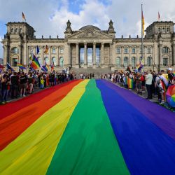 Una bandera arcoíris de 400 m² ondea en el césped frente al Reichstag, sede del Bundestag (cámara baja del Parlamento), en vísperas del Día de la Calle Christopher Street de Berlín. Julia Kloeckner, la nueva presidenta conservadora del parlamento alemán, anunció en mayo que no se izaría la bandera arcoíris durante el evento conocido como el Día de la Calle Christopher Street (DCA). La decisión ha provocado protestas de activistas por los derechos LGBTQ+. | Foto:JOHN MACDOUGALL / AFP