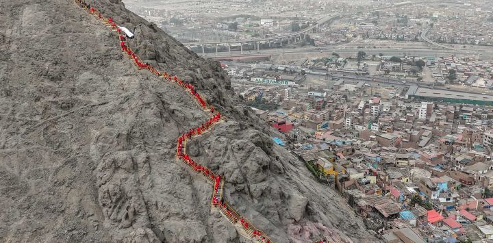 En esta vista aérea, familiares de las víctimas de las protestas antigubernamentales de 2022-2023, vestidos de rojo, participan en una ceremonia conmemorativa en el Cerro San Cristóbal de Lima, Perú.