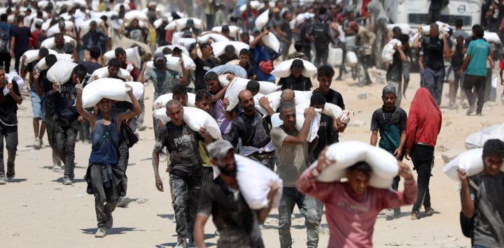 Imagen de palestinos cargando sacos de harina después de que la ayuda humanitaria entrara en Gaza a través de un paso fronterizo, en Beit Lahia, en el norte de la Franja de Gaza.
