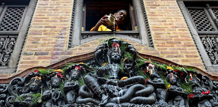 Un devoto vierte leche sobre una estatua de la diosa hindú de las serpientes 'Manasa' con motivo del festival Naga Panchami, cerca de Nagpokhari (estanque de serpientes) en Bhaktapur, en las afueras de Katmandú, Nepal.
