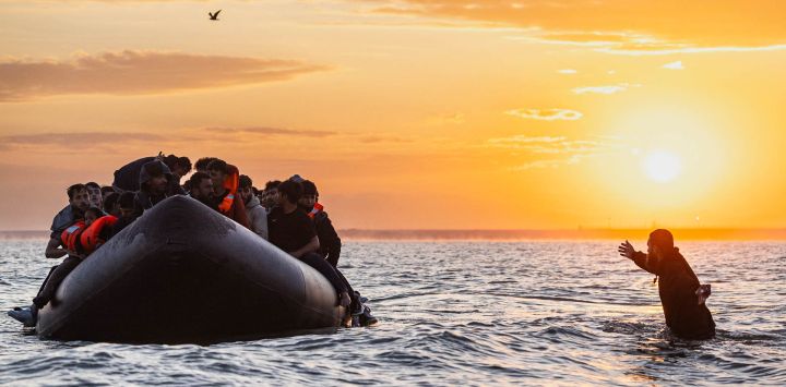 Un migrante intenta subir a la lancha inflable de un contrabandista para intentar cruzar el Canal de la Mancha frente a la playa de Gravelines, en el norte de Francia.