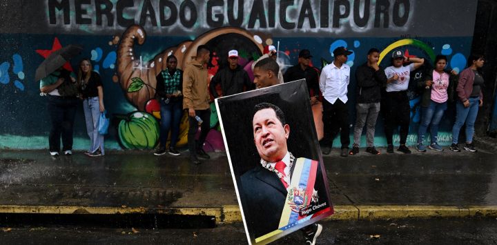 Un partidario del presidente venezolano, Nicolás Maduro, sostiene una imagen del fallecido presidente venezolano, Hugo Chávez, durante una manifestación para celebrar el primer aniversario de su reelección en Caracas.