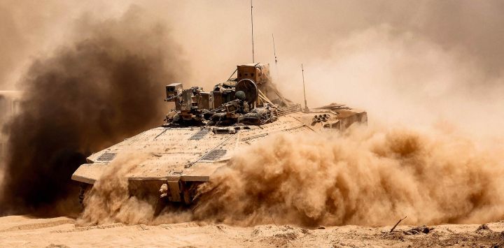Un vehículo de combate de infantería (VCI) del ejército israelí deja una nube de polvo a su paso por la frontera con la Franja de Gaza y el sur de Israel.