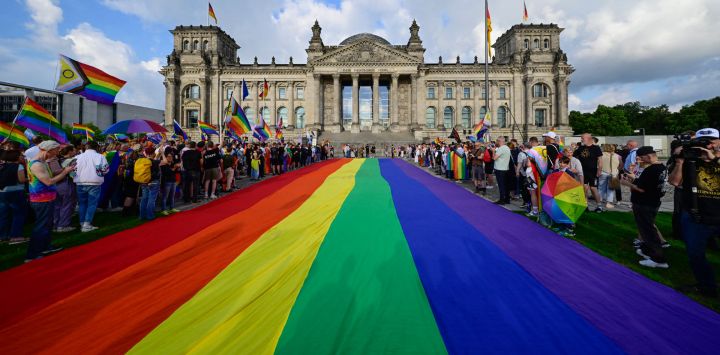 Una bandera arcoíris de 400 m² ondea en el césped frente al Reichstag, sede del Bundestag (cámara baja del Parlamento), en vísperas del Día de la Calle Christopher Street de Berlín. Julia Kloeckner, la nueva presidenta conservadora del parlamento alemán, anunció en mayo que no se izaría la bandera arcoíris durante el evento conocido como el Día de la Calle Christopher Street (DCA). La decisión ha provocado protestas de activistas por los derechos LGBTQ+.