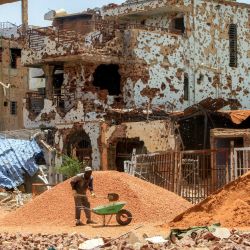 Un trabajador retira piedras de un montículo con una pala y las coloca en una carretilla cerca de unos edificios gravemente dañados en el suburbio de Lamab, en las afueras del suroeste de Jartum, la capital de Sudán, mientras los residentes regresan tras las labores de reconstrucción. | Foto:Ebrahim Hamid / AFP