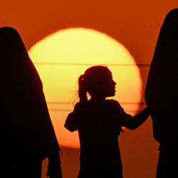 Dos mujeres y una niña marchan junto a otros devotos musulmanes chiítas en el distrito de Midaina, al norte de la provincia iraquí de Basora, al atardecer, rumbo a la ciudad santuario de Karbala para unirse a la peregrinación de Arbain, 40 días después de las conmemoraciones del asesinato en el siglo VII del imán Hussein, nieto del profeta Mahoma. | Foto:Hussein Faleh / AFP