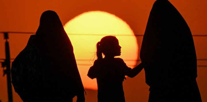 Dos mujeres y una niña marchan junto a otros devotos musulmanes chiítas en el distrito de Midaina, al norte de la provincia iraquí de Basora, al atardecer, rumbo a la ciudad santuario de Karbala para unirse a la peregrinación de Arbain, 40 días después de las conmemoraciones del asesinato en el siglo VII del imán Hussein, nieto del profeta Mahoma.