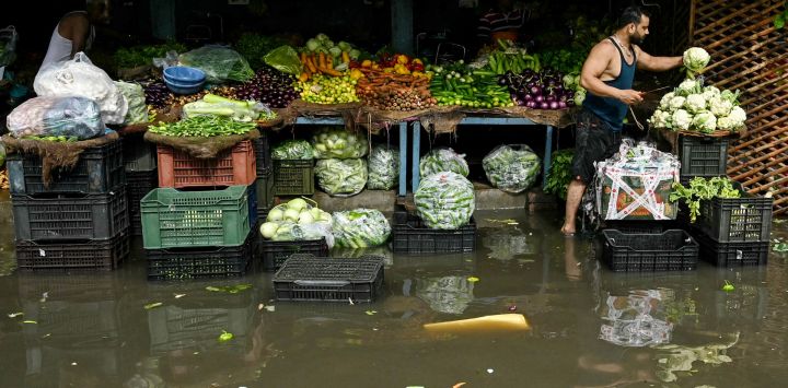 Vendedores de verduras preparan sus provisiones mientras esperan a los clientes en una calle inundada tras fuertes lluvias en Amritsar, India.