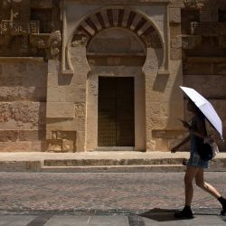 Un turista se protege del sol bajo una sombrilla durante una ola de calor en Córdoba, España. La segunda ola de calor del año comienza en la Península Ibérica. | Foto:JORGE GUERRERO / AFP