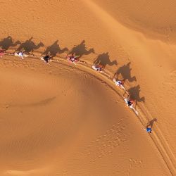 Vista aérea tomada con un dron de personas montando camellos en un área escénica desértica, en la bandera de Dalad de la ciudad de Erdos, en la región autónoma de Mongolia Interior, en el norte de China. | Foto:Xinhua/Lian Zhen