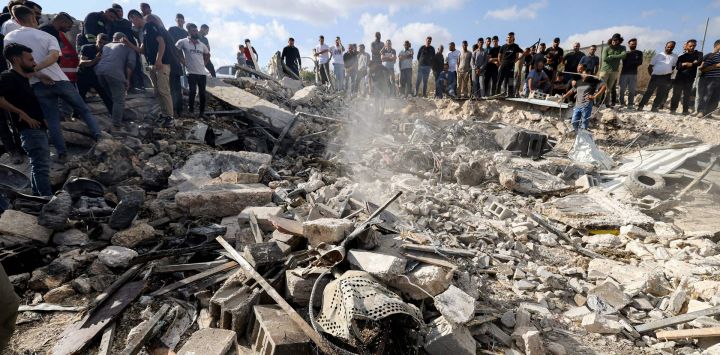 La gente busca entre los escombros de un edificio destruido los cuerpos de las víctimas enterradas allí, tras una operación militar israelí en la aldea de Mirka, a unos 12 kilómetros al suroeste de Yenín, en la Cisjordania ocupada.