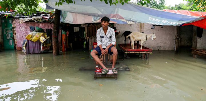 Un hombre se sienta frente a su casa, parcialmente inundada por las fuertes lluvias monzónicas que provocaron un aumento del nivel del río Ganges en Varanasi, India.