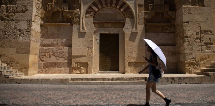 Un turista se protege del sol bajo una sombrilla durante una ola de calor en Córdoba, España. La segunda ola de calor del año comienza en la Península Ibérica.