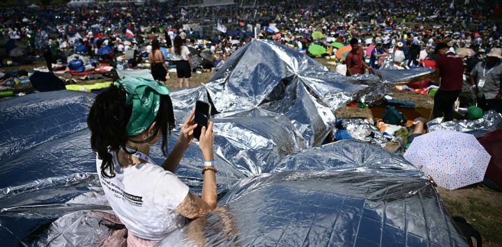 Una mujer usa su teléfono inteligente mientras jóvenes y peregrinos se reúnen en el barrio de Tor Vergata, al este de Roma, para una vigilia de oración dirigida por el Papa antes de la misa, en el marco del Jubileo de la Juventud.