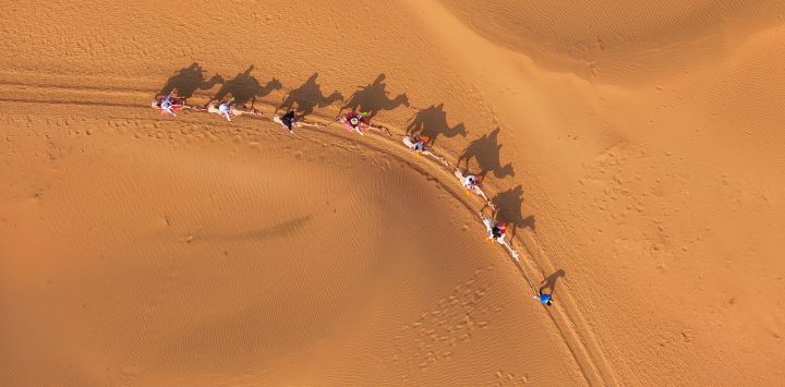 Vista aérea tomada con un dron de personas montando camellos en un área escénica desértica, en la bandera de Dalad de la ciudad de Erdos, en la región autónoma de Mongolia Interior, en el norte de China.