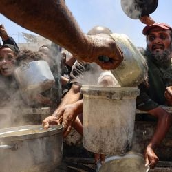 Palestinos reciben sopa de lentejas en un punto de distribución de alimentos en la ciudad de Gaza. La Organización Mundial de la Salud advirtió que la desnutrición estaba alcanzando niveles alarmantes en Gaza. | Foto:OMAR AL-QATTAA / AFP