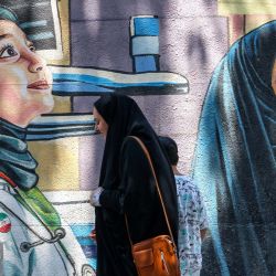 Una mujer iraní pasa junto a un mural en Teherán. | Foto:ATTA KENARE / AFP