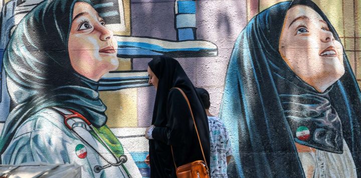 Una mujer iraní pasa junto a un mural en Teherán.