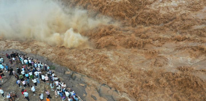 Vista aérea tomada por un dron de personas visitando la cascada Hukou en el río Amarillo, en el distrito de Jixian, en la provincia de Shanxi, en el norte de China. La cascada Hukou está experimentando un aumento del caudal de agua últimamente.