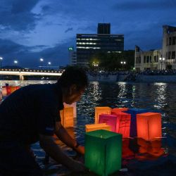 Voluntarios colocan linternas de papel en el río Motoyasu, frente a la Cúpula de la Bomba Atómica, después de que los visitantes las soltaran para conmemorar el 80.º aniversario del primer ataque con bomba atómica, ocurrido en la ciudad de Hiroshima. | Foto:Richard A. Brooks / AFP