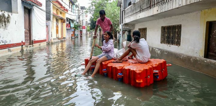 Niños viajan en un muelle flotante en una zona residencial inundada después de que las fuertes lluvias monzónicas provocaran un aumento del nivel del agua del río Ganges en Varanasi, India.