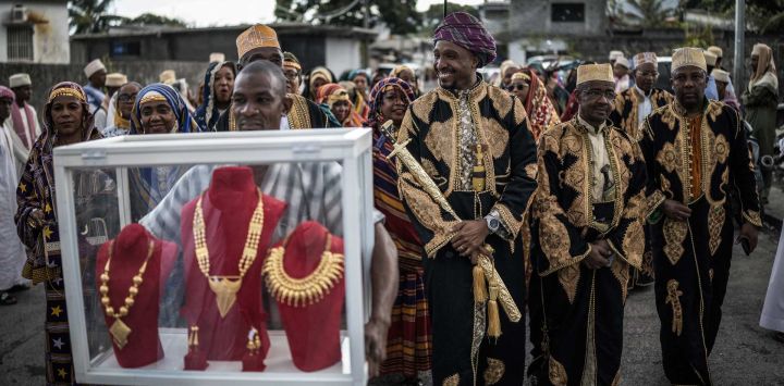 Porteadores llevan vitrinas con la dote de oro que el francocomorense Faid Kassime (centro), residente en Reunión con su esposa Faizat Aboubacar, llevará a la casa de la familia de su novia en Moroni durante la ceremonia del Gran Matrimonio.