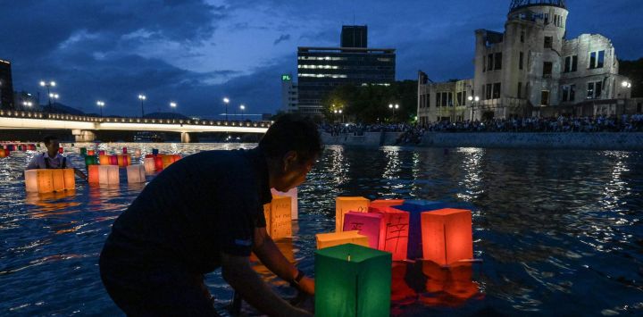 Voluntarios colocan linternas de papel en el río Motoyasu, frente a la Cúpula de la Bomba Atómica, después de que los visitantes las soltaran para conmemorar el 80.º aniversario del primer ataque con bomba atómica, ocurrido en la ciudad de Hiroshima.