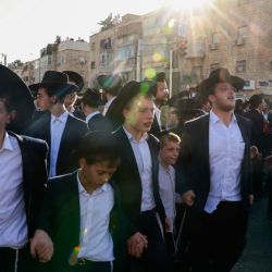 Manifestantes judíos ultraortodoxos corean cánticos tomados de la mano mientras protestan por su reclutamiento en el ejército israelí y el arresto de estudiantes de escuelas religiosas que evadieron las órdenes de reclutamiento, durante una manifestación en Jerusalén. | Foto:MENAHEM KAHANA / AFP