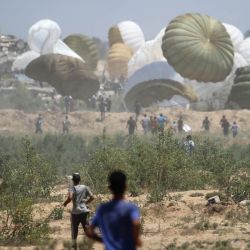 Palestinos acuden rápidamente al lugar donde aterrizan los paquetes de ayuda en paracaídas en la zona de Nuseirat, en el centro de la Franja de Gaza, durante un lanzamiento aéreo sobre el territorio palestino asediado por Israel. | Foto:Eyad Baba / AFP