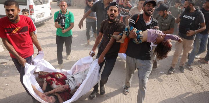 Hombres palestinos transportan los cuerpos de los niños de la familia Irhim, asesinados en un ataque israelí en el distrito de Zaitun, al hospital Al-Shifa de la ciudad de Gaza.