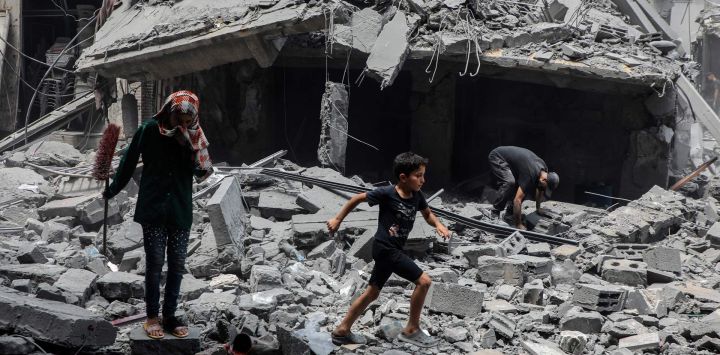 Imagen de palestinos inspeccionando los daños tras un ataque aéreo israelí en el área de Al-Rimal, en el oeste de la Ciudad de Gaza.
