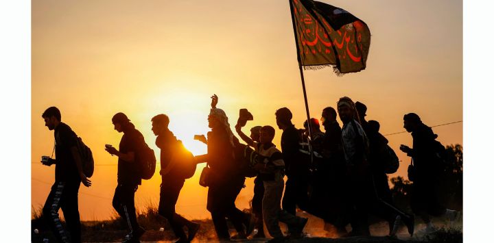 Peregrinos musulmanes chiítas marchan con banderas y pancartas en el distrito de Shamiya, al sur de Diwaniya, ciudad central de Irak, rumbo a la ciudad sagrada de Karbala antes de las conmemoraciones de Arbain.