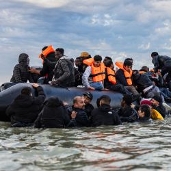 Migrantes intentan subir a un barco de contrabandistas para intentar cruzar el Canal de la Mancha frente a la playa de Gravelines, en el norte de Francia. | Foto:SAMEER Al-DOUMY / AFP