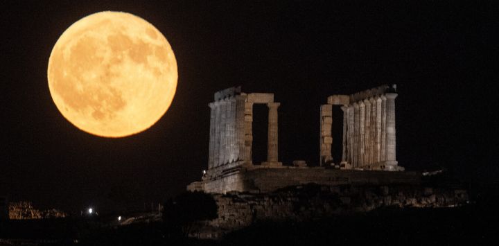 Imagen de una luna llena elevándose sobre el Antiguo Templo de Poseidón en el Cabo Sunión, en Sunión, Grecia.